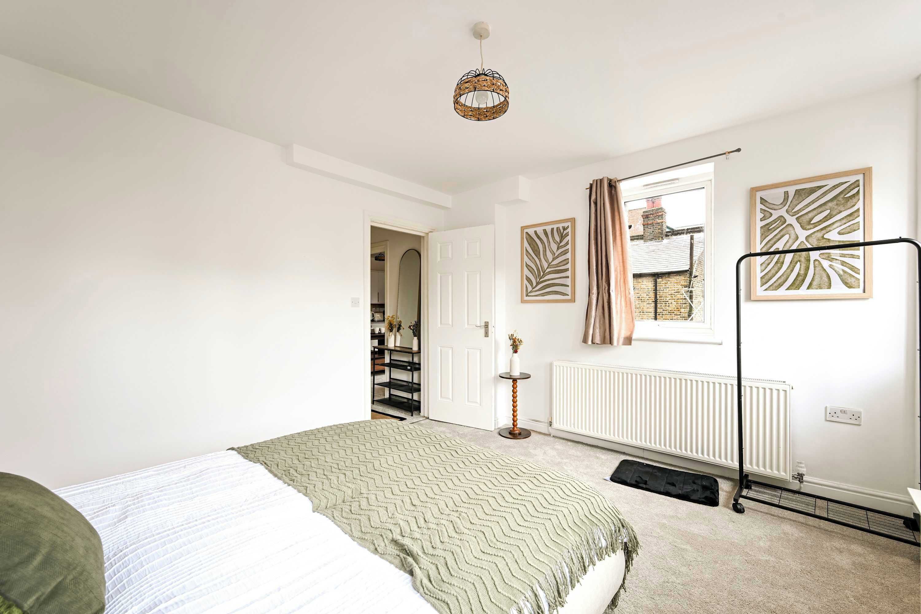 Een slaapkamer met een bed, een radiator, een deur en een raam.