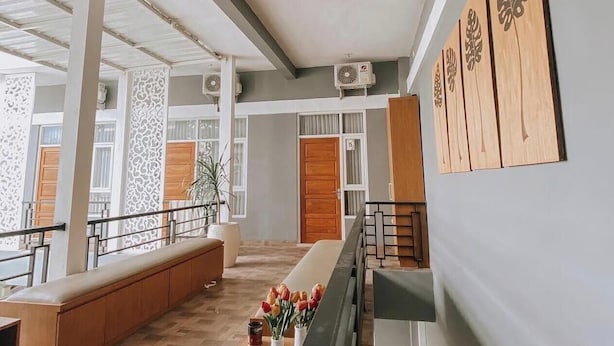 Un intérieur spacieux comprenant un long banc, un escalier et un mur orné de panneaux décoratifs.