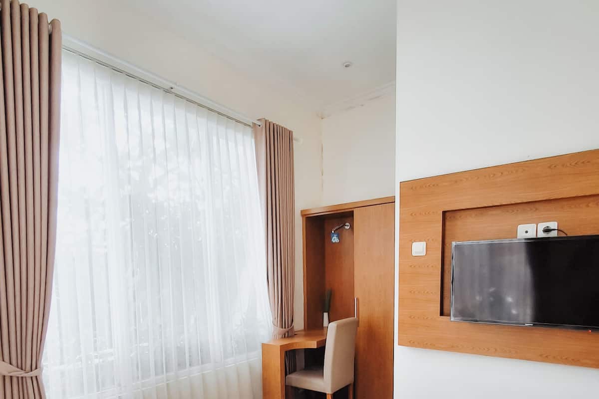 A hotel room with a bed, a desk, a chair, and a television mounted on the wall.