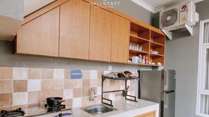Une cuisine avec des meubles en bois, un réfrigérateur en acier inoxydable, un évier et un dosseret carrelé.