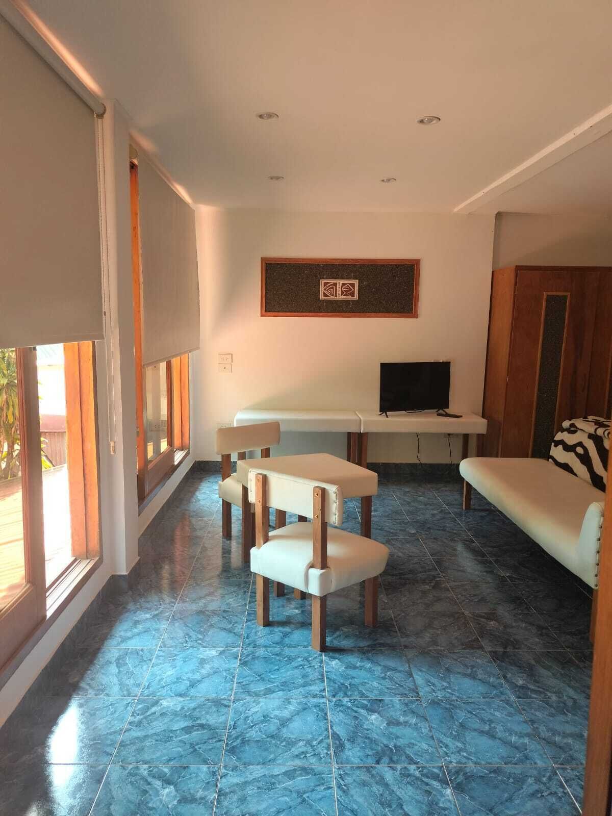Una sala de estar con sofá, televisión, mesa de comedor y una silla.
