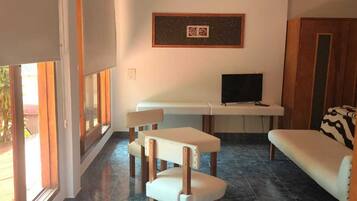 Una sala de estar con sofá, televisión, mesa de comedor y una silla.
