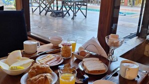 Una mesa de desayuno con platos de comida, un vaso de jugo de naranja y una taza de café.