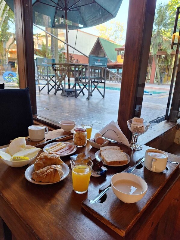 Una mesa de desayuno con platos de comida, un vaso de jugo de naranja y una taza de café.