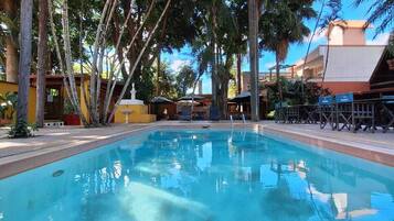 Una piscina al aire libre, sombrillas, sillones reclinables de piscina