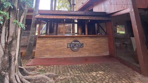 A rustic building with a wooden facade, a sign reading 'Pizzeria Il Porto,' and a cobblestone ground. - La Locanda Art & Taste Retreat (Puerto Iguazú)