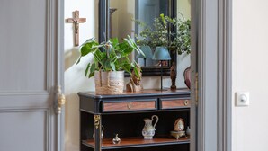 Een houten dressoir met laden, een spiegel en diverse decoratieve items, waaronder een kruis, planten en beeldjes.