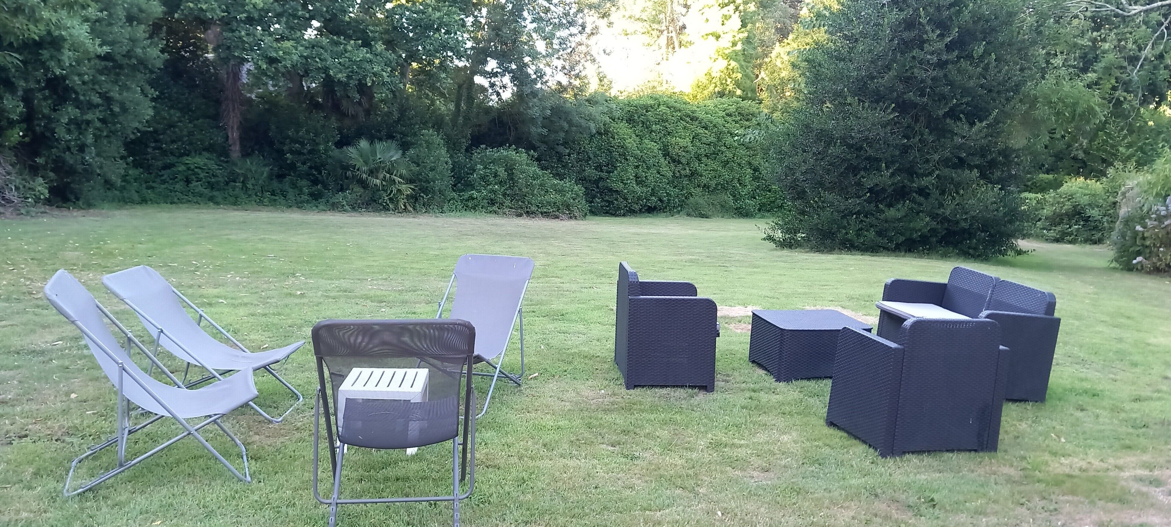 Un espacio al aire libre con césped y un conjunto de mobiliario con sillas y una mesa.