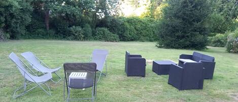 Un espacio al aire libre con césped y un conjunto de mobiliario con sillas y una mesa.