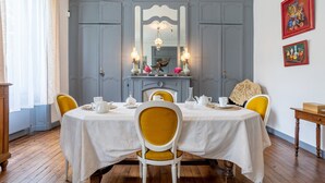 Comedor con una mesa preparada para cuatro, sillas, un espejo y decoración en la pared.