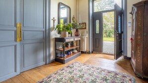 Un pasillo con piso de madera, un tapete estampado, un mueble de madera oscura, un espejo y una estantería con adornos.