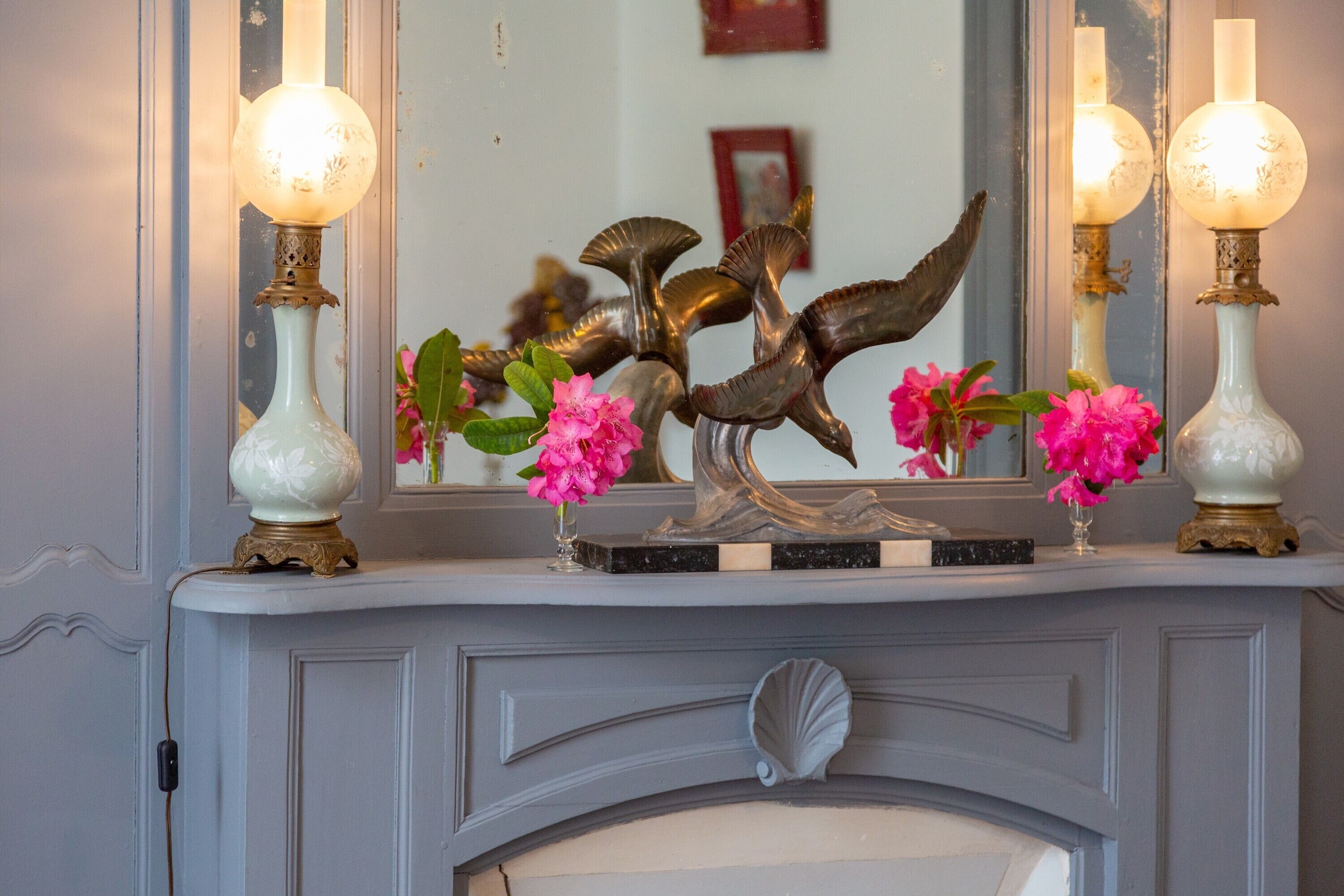A fireplace mantel with decorative items, including a mirror, vases, and a sculpture.