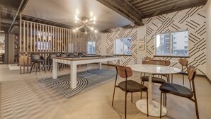 Ein modernes Interieur mit einem runden Tisch und Stühlen, einer Wand mit Muster und einer Decke mit freiliegenden Balken.