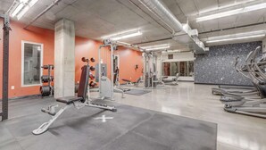 Ein Fitnessstudio mit Gewichthebern, Laufbändern und einer Spiegelwand.