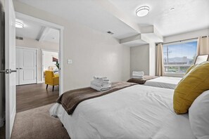 Habitación de hotel con dos camas, vistas a la ciudad y una silla amarilla.