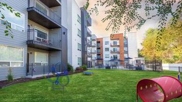 A modern apartment complex with balconies, a playground, and a red slide.
