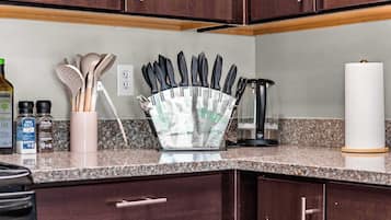 A kitchen counter with a knife block, a paper towel holder, and a bottle of olive oil.
