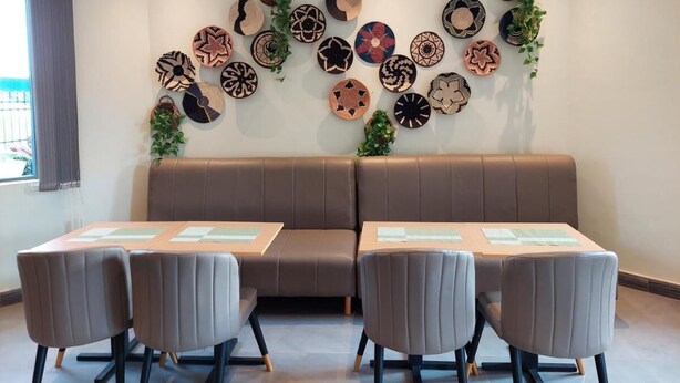 Um quarto com um sofá castanho, quatro cadeiras cinzentas e uma parede decorada com peças de arte em tecido circular.