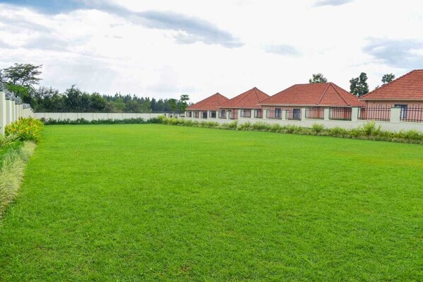 A row of buildings with red roofs, a green lawn, and a white fence.