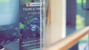Uma vitrine de vidro com um folheto turístico para passeios e viagens em Uganda.
