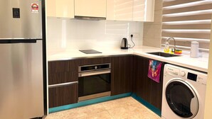 A modern kitchen with a stainless steel refrigerator, a built-in oven, a dishwasher, and a sink with a window above. - THE MANOR CLASIC SUITES BY BUKIT BINTANG (Kuala Lumpur)