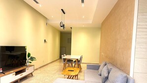 A modern living room with a sofa, a TV, a dining table, and a potted plant. - THE MANOR CLASIC SUITES BY BUKIT BINTANG (Kuala Lumpur)