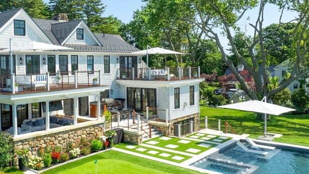 A two-story house with a deck, a swimming pool, and a stone wall. - Luxurious expansive villa in prestigious Watch Hill set on 5 acres (Westerly)