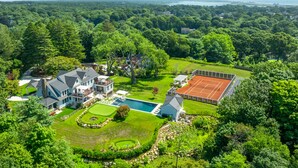 A large house with a tennis court, swimming pool, and lush green surroundings. - Luxurious expansive villa in prestigious Watch Hill set on 5 acres (Westerly)