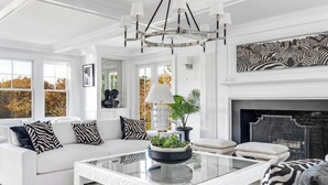 A spacious living room with a white sofa, a glass coffee table, and a fireplace.