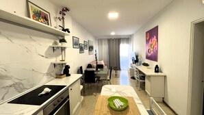 Een moderne keuken met een marmeren aanrecht, een eethoek met tafel en stoelen, en een zithoek met een bank en televisie.