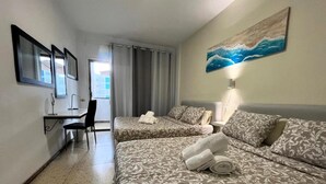 Een hotelkamer met twee bedden, een bureau, een stoel en een schilderij aan de muur.
