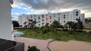 Een meerlaags hotel met een binnenplaats, met palmbomen en een zwembad.