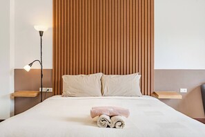 A hotel room with a bed, two bedside tables, a lamp, and a wall-mounted shelf. - Cozy 1-bedroom Apartment With Kitchen and Bathroom Near Kata Beach, Thailand (Karon)