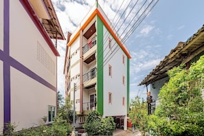 A multi-story building with balconies, a visible window, and a small garden area. - Cozy 1-bedroom Apartment With Kitchen and Bathroom Near Kata Beach, Thailand (Karon)