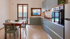 Una cocina moderna con comedor, que cuenta con un amplio ventanal, electrodomésticos integrados y vistas al exterior.