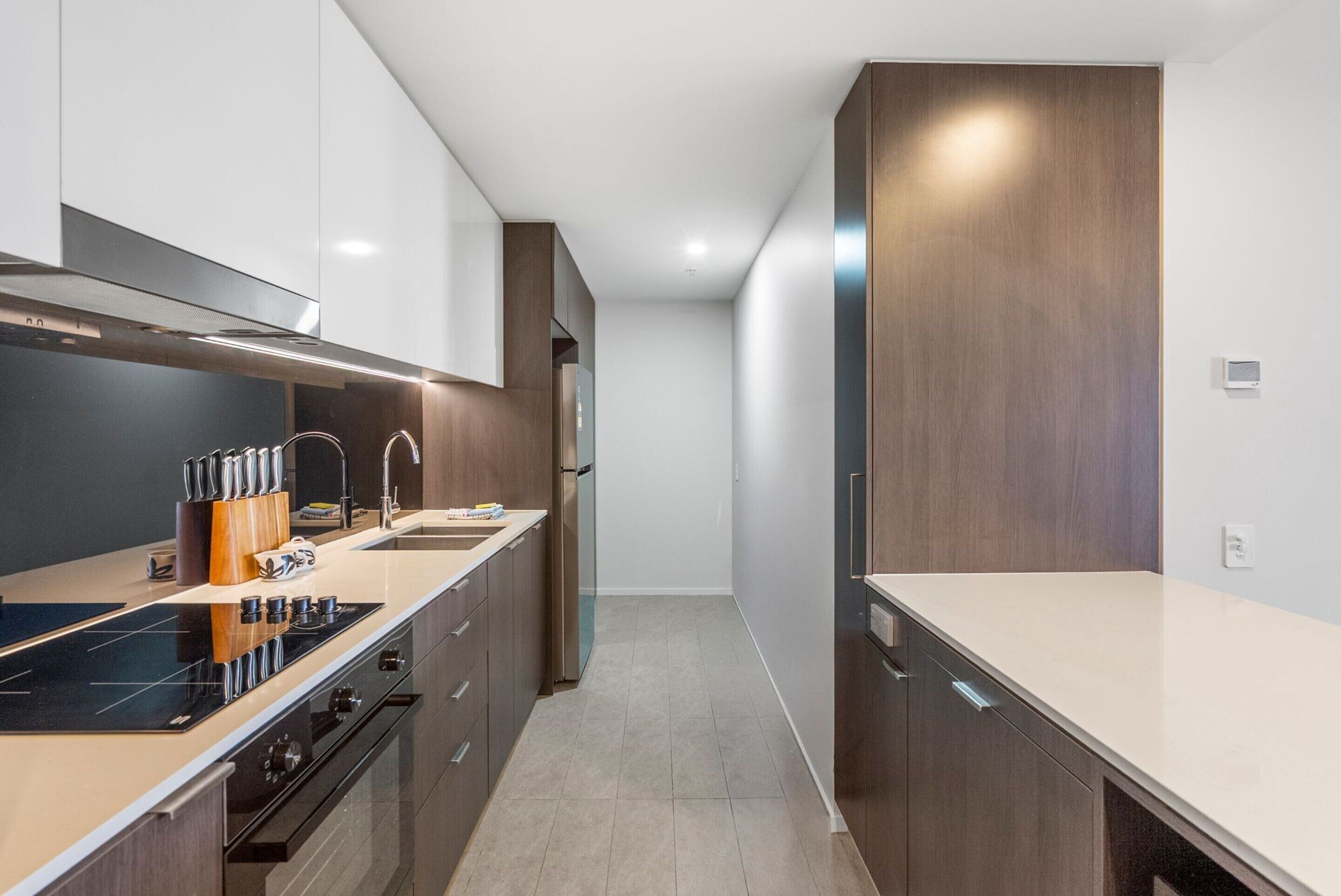 A modern kitchen with a central island, stainless steel appliances, and wooden cabinetry.