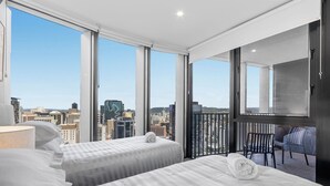 A hotel room with two beds, a large window, a balcony with chairs, and a city view. - Bright Apartment With Pool and Gym Access (Brisbane)