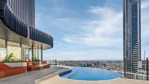 A rooftop pool with a city view, modern architecture, and a clear sky. - Bright Apartment With Pool and Gym Access (Brisbane)
