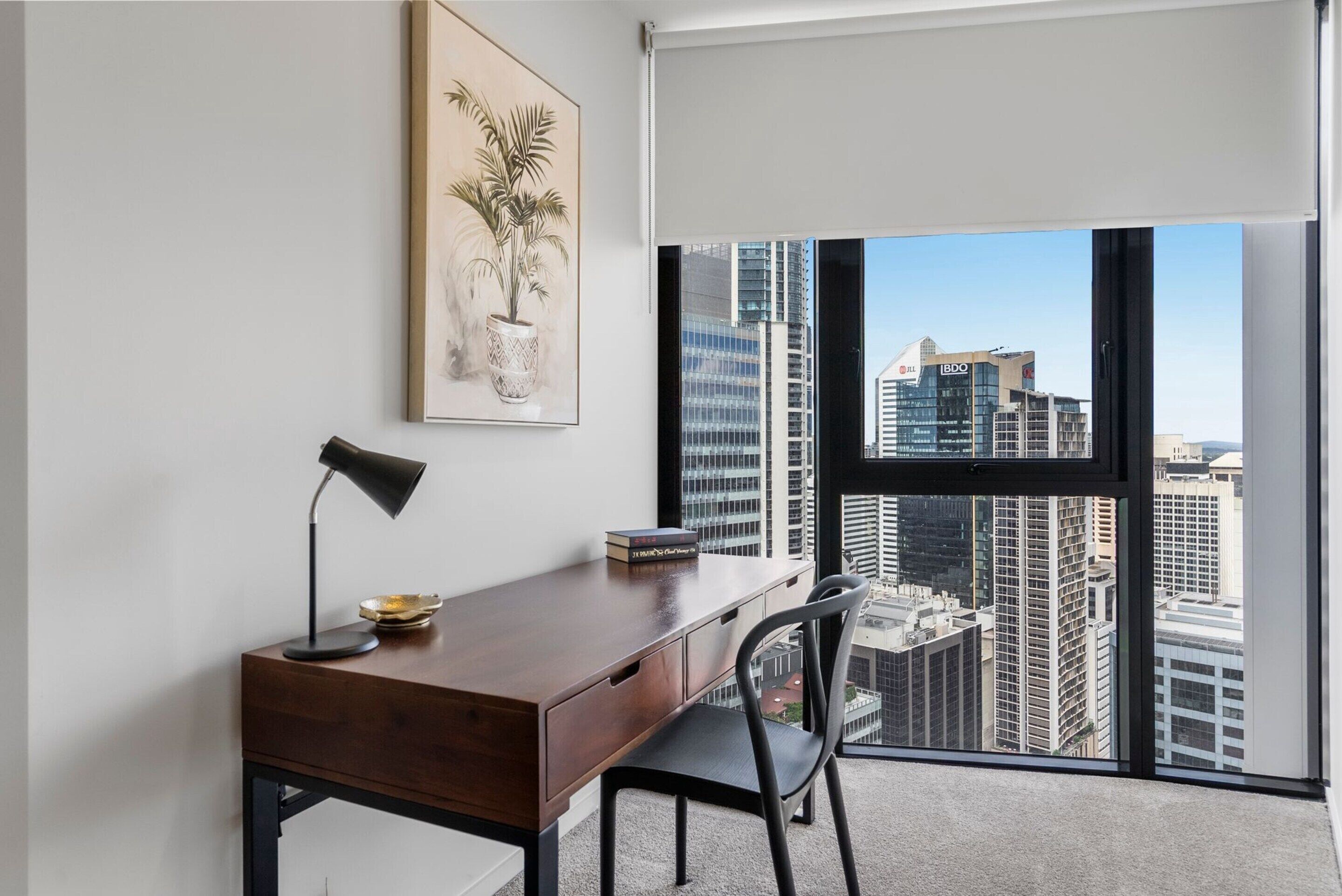 A modern office space with a desk, chair, and a large window offering a city view.