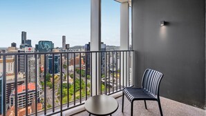 A balcony with a view of a cityscape, a chair, and a table. - Bright Apartment With Pool and Gym Access (Brisbane)