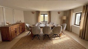 Uma sala de jantar com um aparador de madeira, um tapete grande e vista para o exterior através de uma janela.