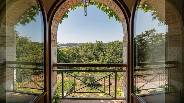 Quarto com uma grande janela em arco, oferecendo vista para uma paisagem exuberante.