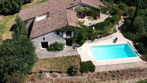 Uma casa com piscina, fachada de pedra e jardim.