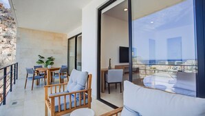 Een balkon met zitplaatsen, een eethoek en een groot raam met uitzicht op de stad.