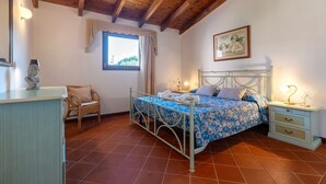 A bedroom with a bed, a nightstand, a chair, a dresser, and a window with curtains. - Villa 'Armonia - Private Pool' with Private Pool, Wi-Fi and Air Conditioning (Punta de Su Turrione)