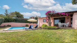 A backyard with a swimming pool, lounge chairs, a table with chairs, and a pergola with flowers. - Villa 'Armonia - Private Pool' with Private Pool, Wi-Fi and Air Conditioning (Punta de Su Turrione)