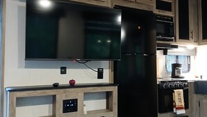 Eine moderne Küche mit eingebauten Geräten, Holzschränken und einem Flachbildfernseher.