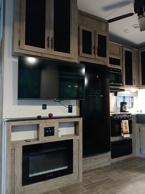 Een moderne keuken met inbouwapparatuur, houten keukenkastjes en een flatscreen televisie.