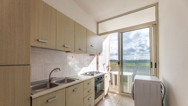 A modern kitchen with a large window, a dining area, and a view of the countryside. - 2 Bedroom Apartment in Rivabella di Gallipoli RB152 (Rivabella)