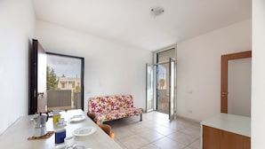 A modern kitchen with a dining area, a sofa, and a sliding glass door leading to an outdoor space. - 2 Bedroom Apartment in Rivabella di Gallipoli RB152 (Rivabella)